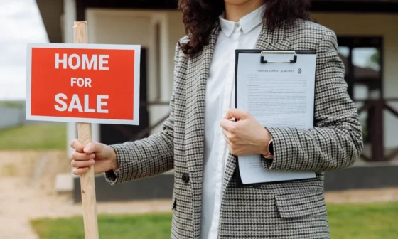 Mujer sosteniendo un cartel de "casa en venta" - captar propiedades para vender